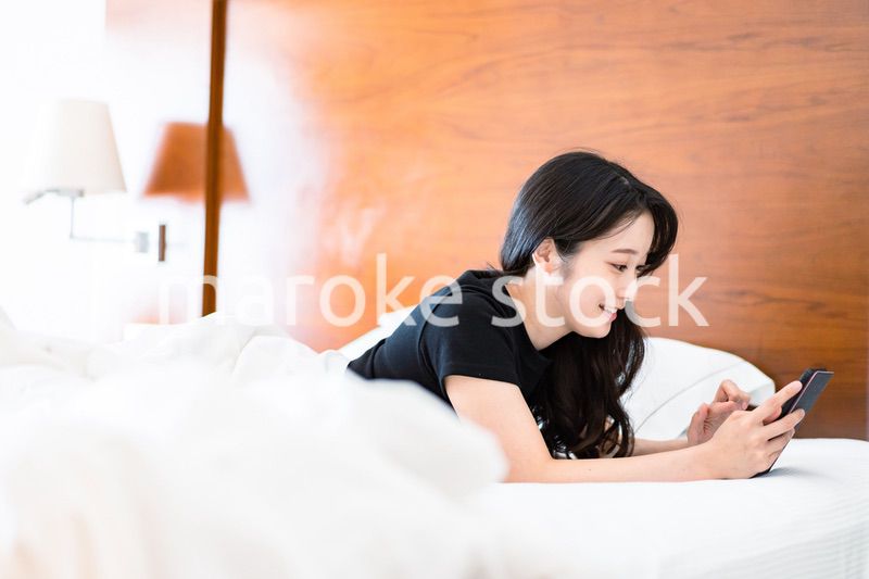 ベッドで電子書籍を読む若い女性