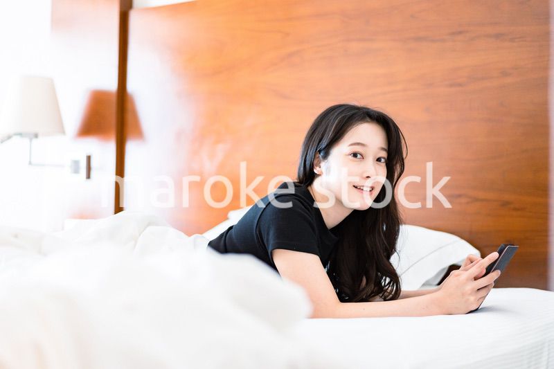 ベッドで電子書籍を読む若い女性