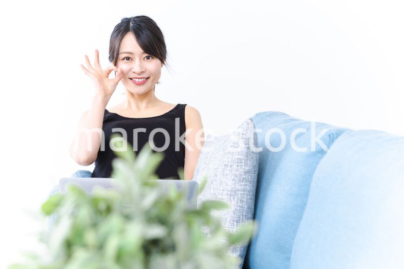 ソファでOKサインをする若い女性