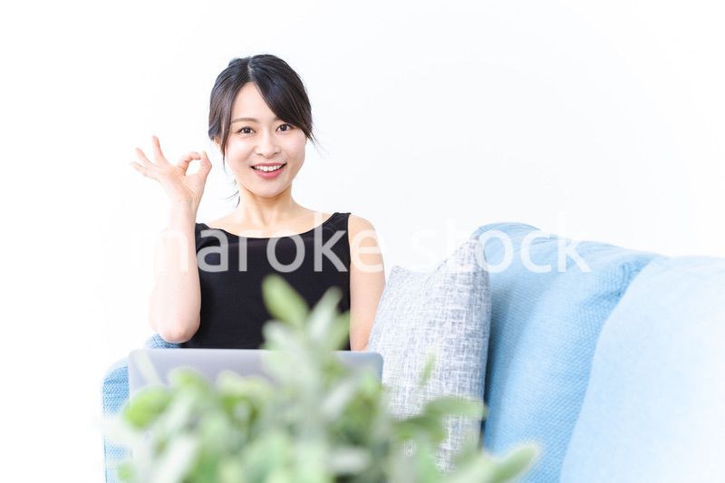 ソファでOKサインをする若い女性