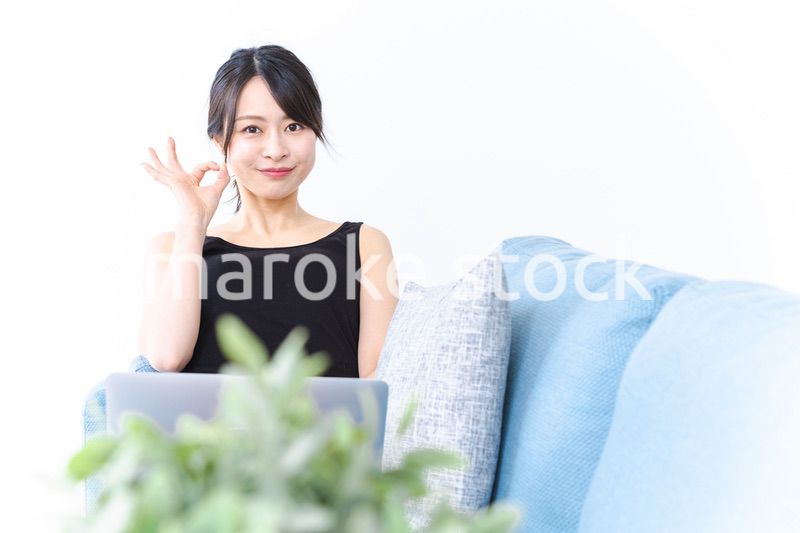 ソファでOKサインをする若い女性