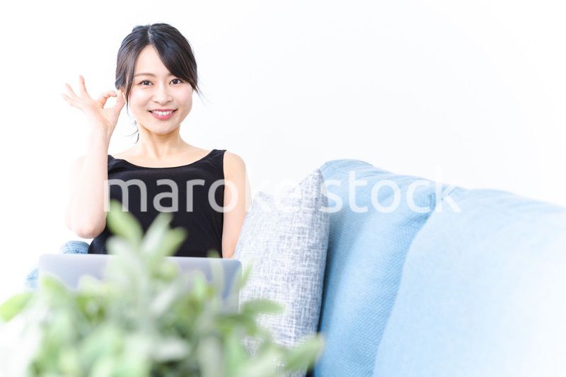 ソファでOKサインをする若い女性