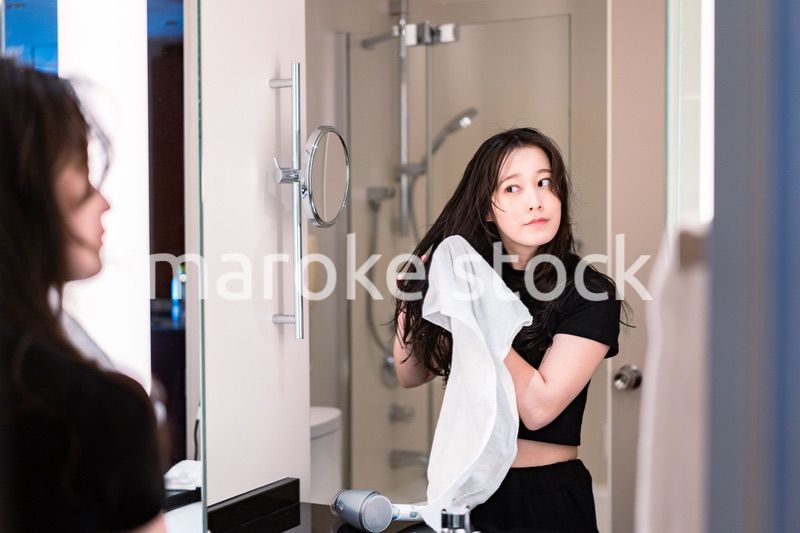 ドライヤーで髪を乾かす若い女性