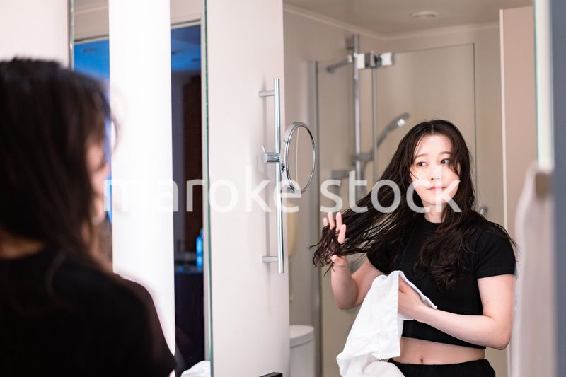 ドライヤーで髪を乾かす若い女性