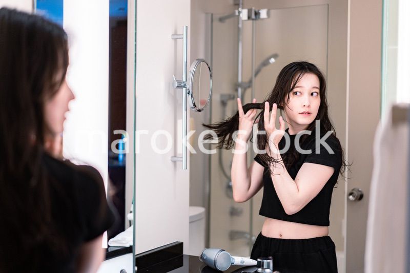 ドライヤーで髪を乾かす若い女性