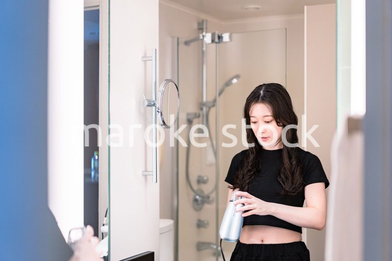 ドライヤーで髪を乾かす若い女性