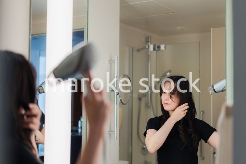 ドライヤーで髪を乾かす若い女性