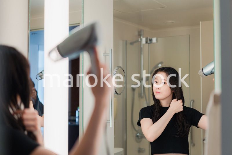 ドライヤーで髪を乾かす若い女性