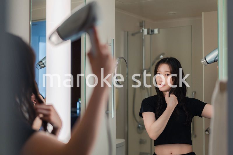 ドライヤーで髪を乾かす若い女性