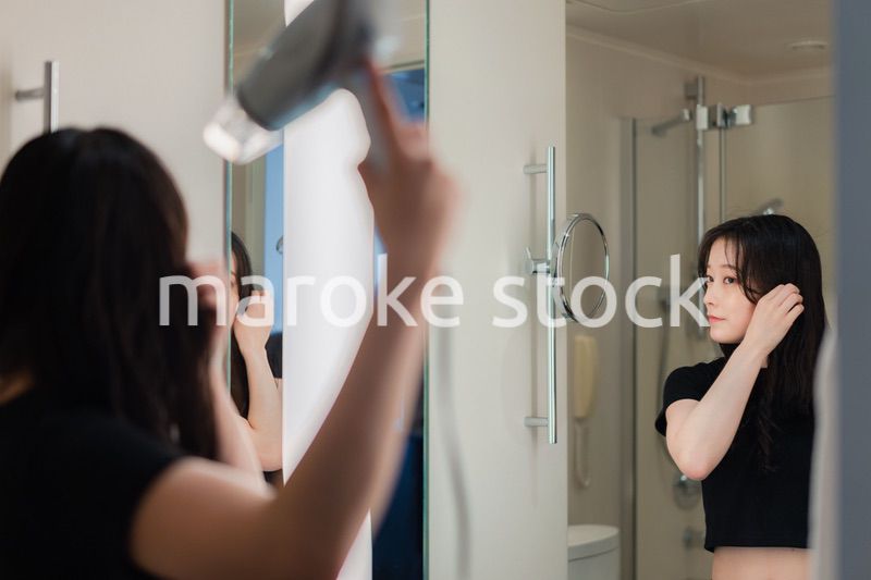 ドライヤーで髪を乾かす若い女性