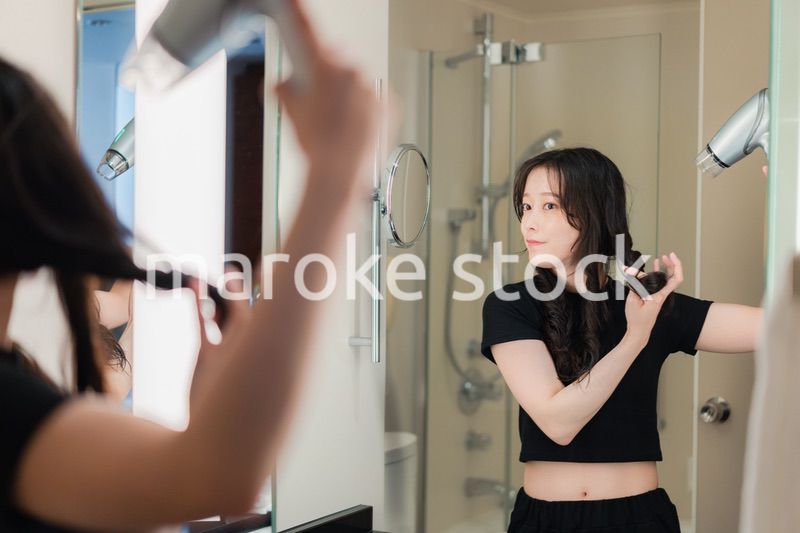 ドライヤーで髪を乾かす若い女性