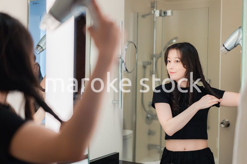 ドライヤーで髪を乾かす若い女性