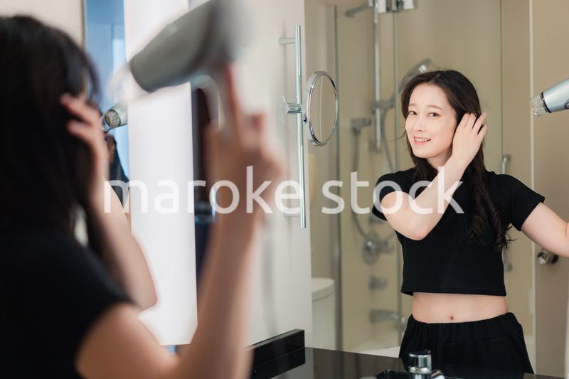 ドライヤーで髪を乾かす若い女性