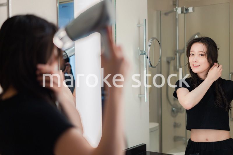 ドライヤーで髪を乾かす若い女性