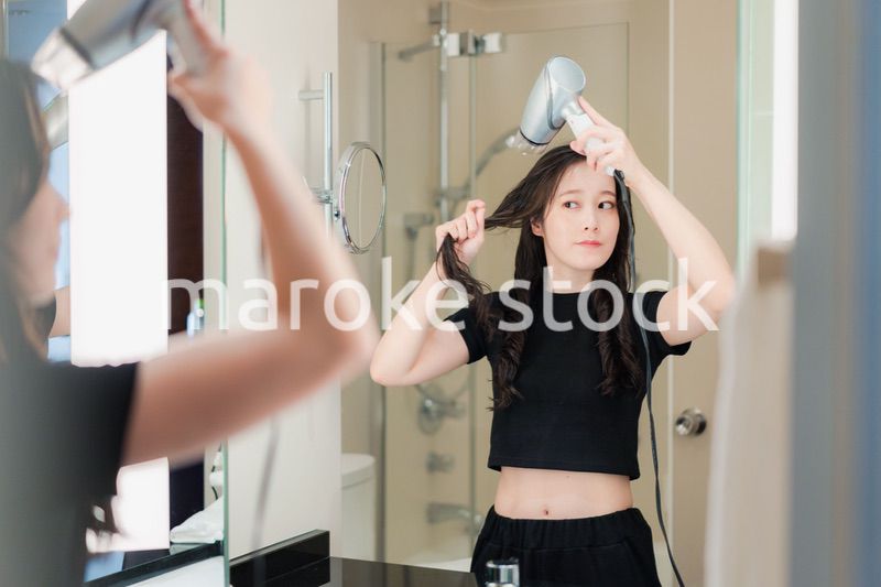 ドライヤーで髪を乾かす若い女性
