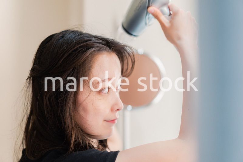 ドライヤーで髪を乾かす若い女性