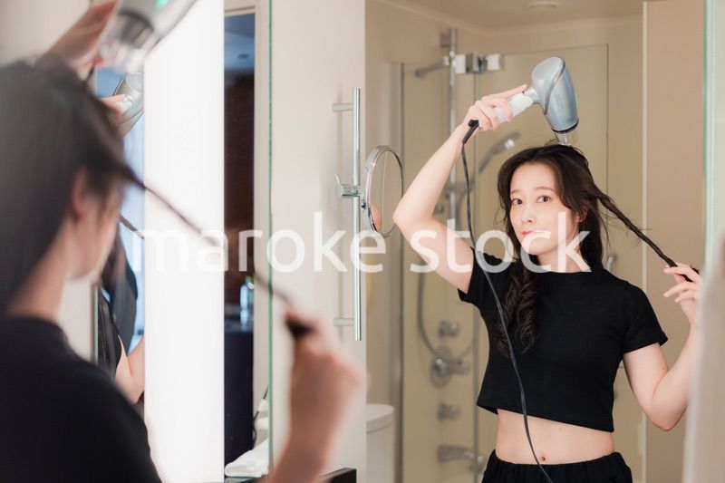 ドライヤーで髪を乾かす若い女性