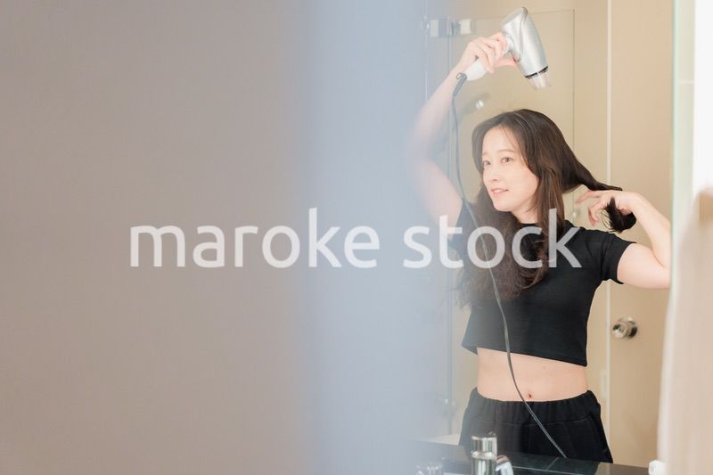 ドライヤーで髪を乾かす若い女性