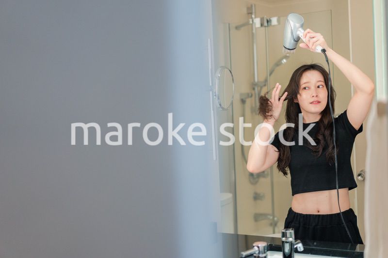 ドライヤーで髪を乾かす若い女性