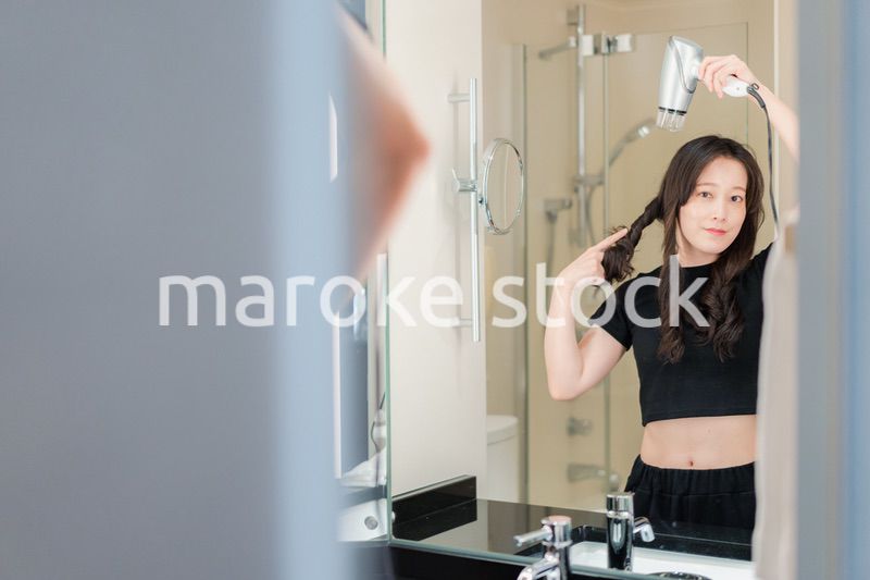 ドライヤーで髪を乾かす若い女性