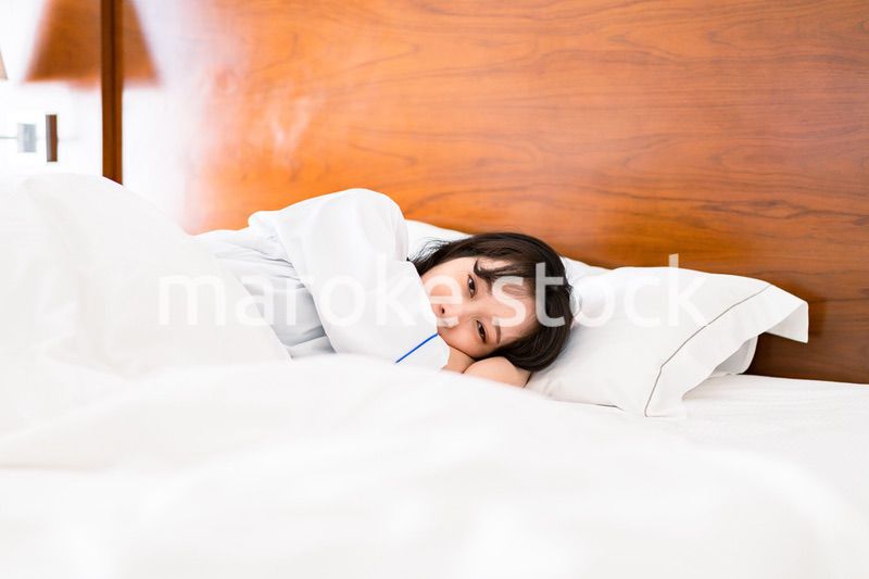 明るい時間にベッドで寝る若い女性