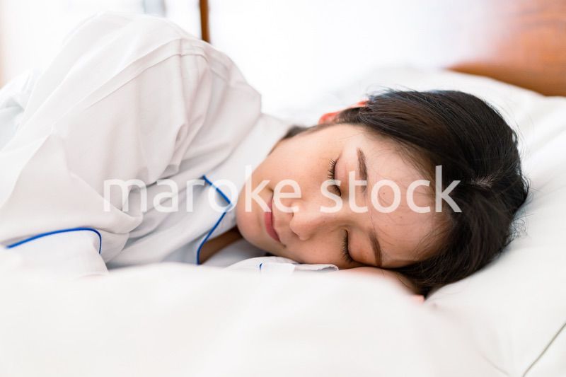 明るい時間にベッドで寝る若い女性