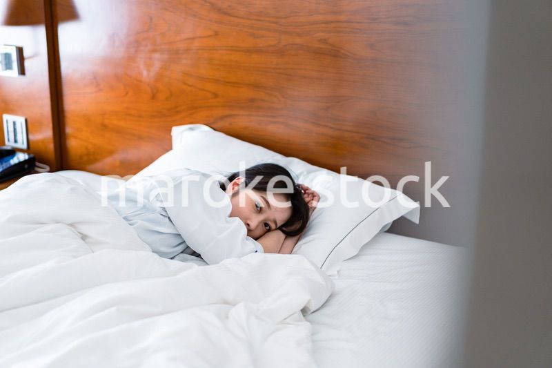 明るい時間にベッドで寝る若い女性