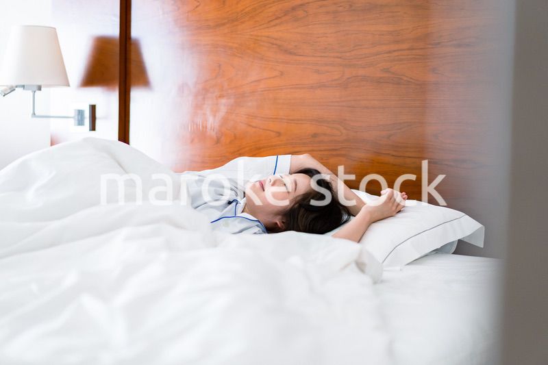 明るい時間にベッドで寝る若い女性