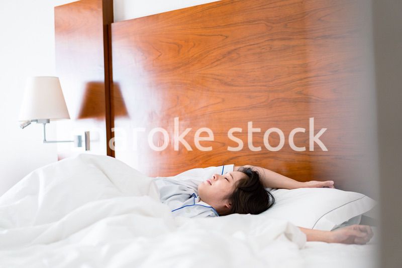 明るい時間にベッドで寝る若い女性