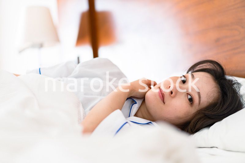 明るい時間にベッドで寝る若い女性