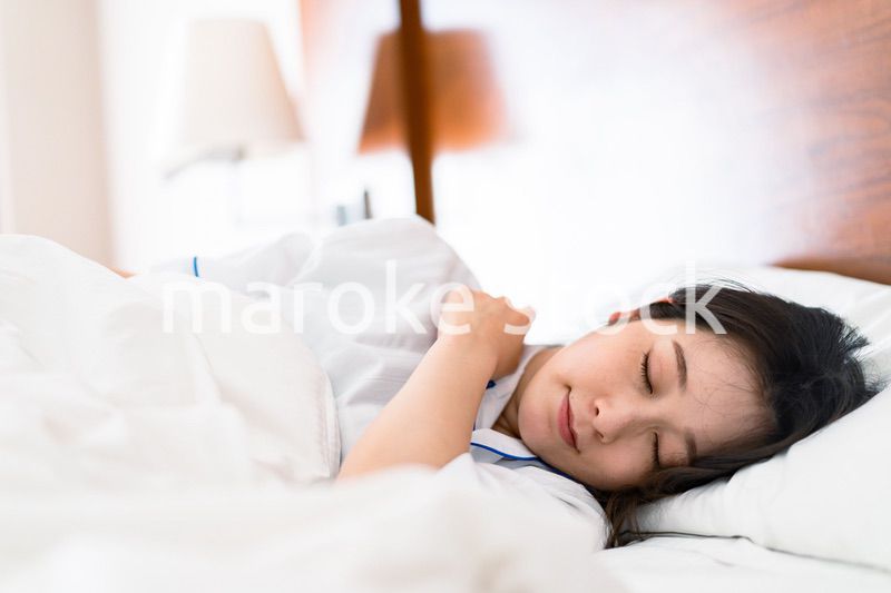 明るい時間にベッドで寝る若い女性