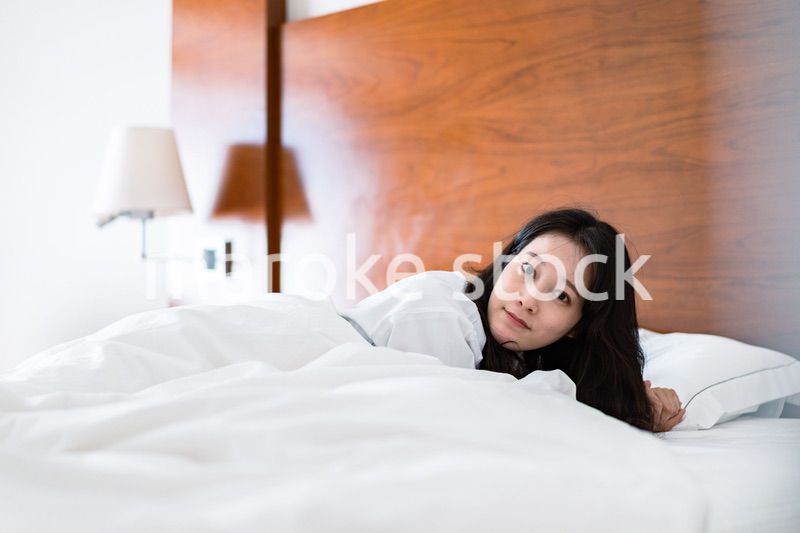 明るい時間にベッドで寝る若い女性