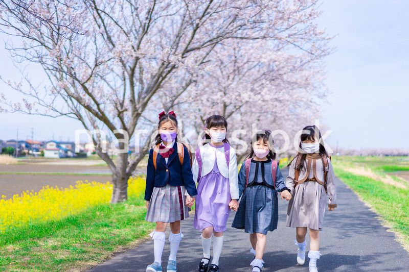 マスクをして小学校に登校する女の子たち
