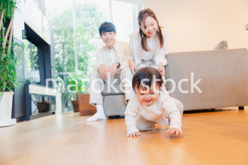 ハイハイをする赤ちゃんと子供の成長を見守る両親