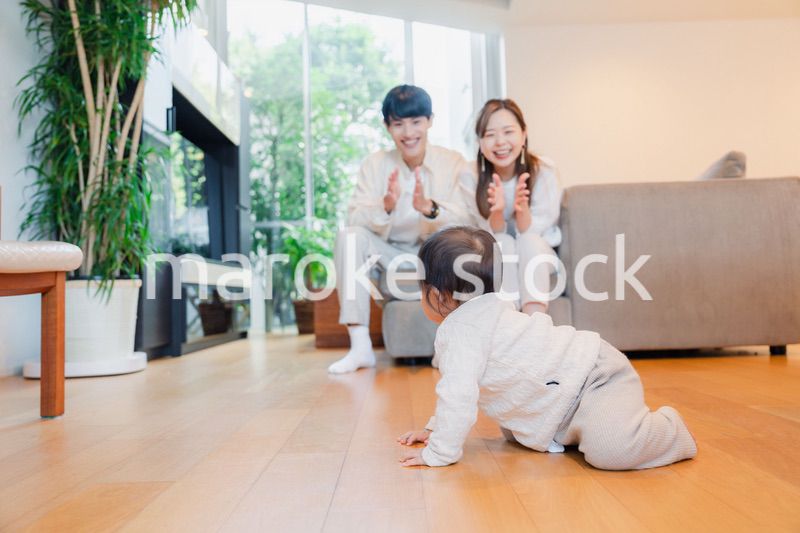 ハイハイをする赤ちゃんと子供の成長を見守る両親