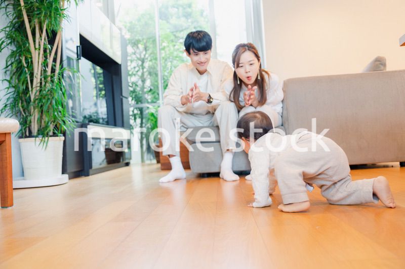 ハイハイをする赤ちゃんと子供の成長を見守る両親