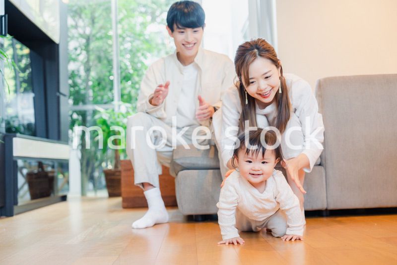 ハイハイをする赤ちゃんと子供の成長を見守る両親