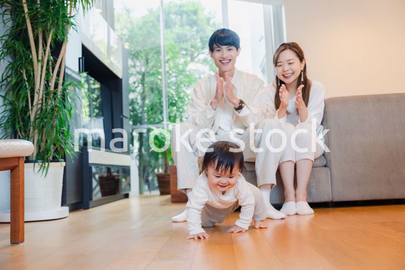 ハイハイをする赤ちゃんと子供の成長を見守る両親