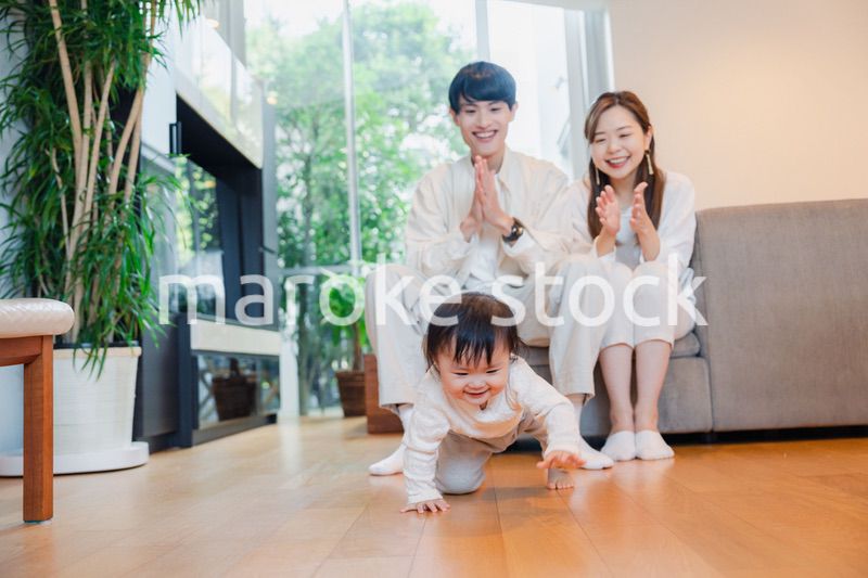 ハイハイをする赤ちゃんと子供の成長を見守る両親
