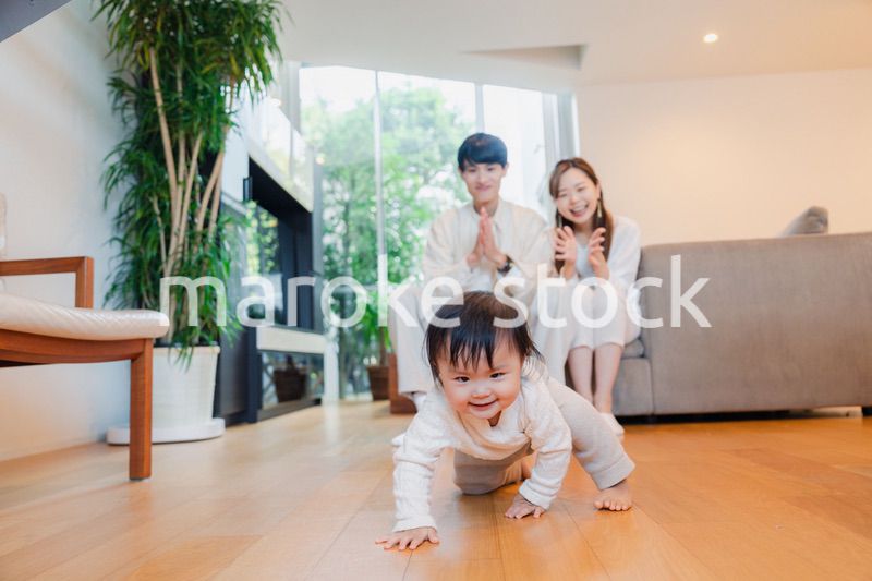 ハイハイをする赤ちゃんと子供の成長を見守る両親