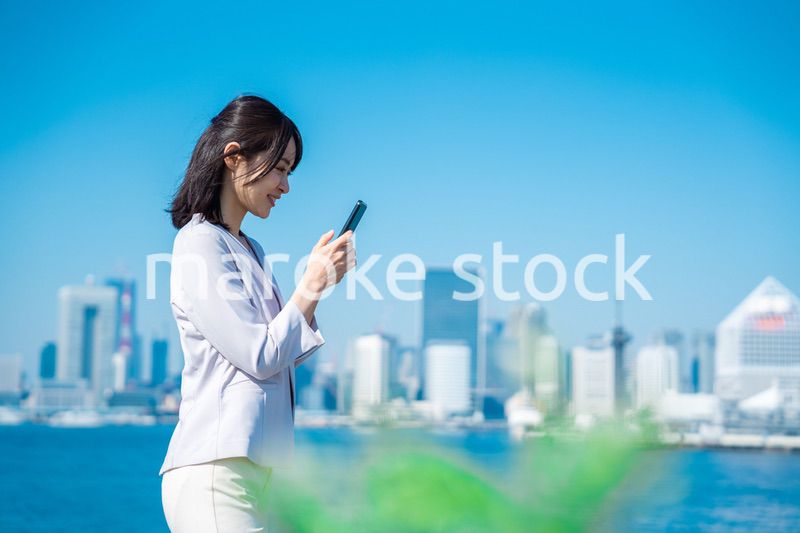 外でスマホを使う若いビジネスウーマン