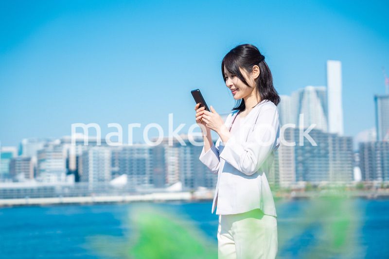 外でスマホを使う若いビジネスウーマン