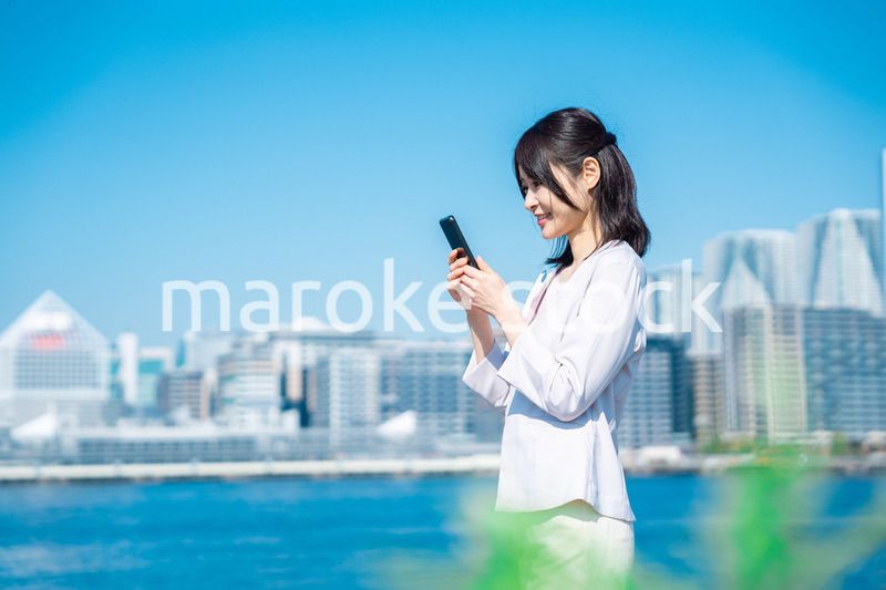 外でスマホを使う若いビジネスウーマン