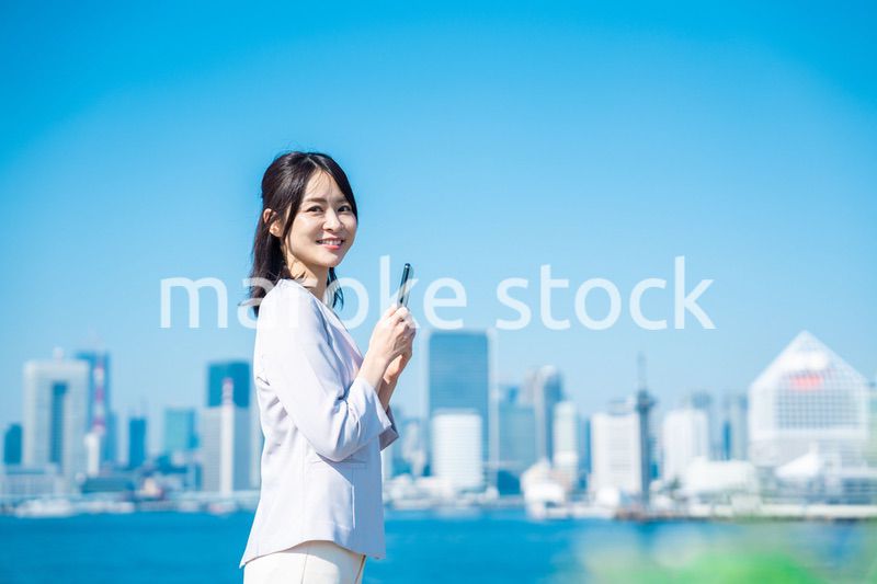 外でスマホを使う若いビジネスウーマン