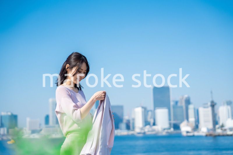 ジャケットを脱いで外を歩くビジネスウーマン