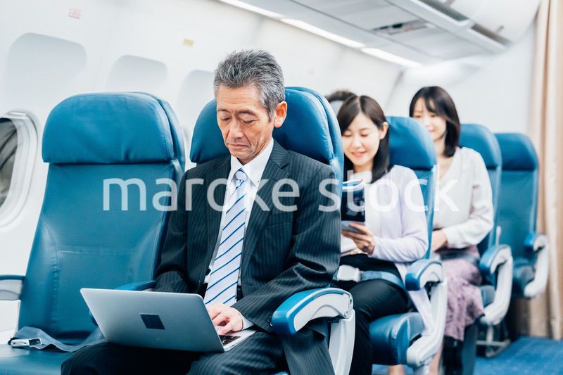 飛行機で出張に出かけるミドルのビジネスマン