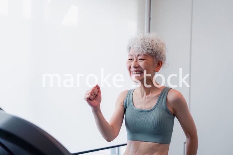 ジムでランニングマシンに乗るシニアの女性