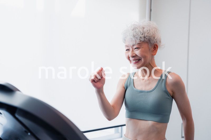ジムでランニングマシンに乗るシニアの女性
