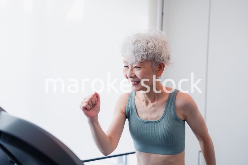 ジムでランニングマシンに乗るシニアの女性