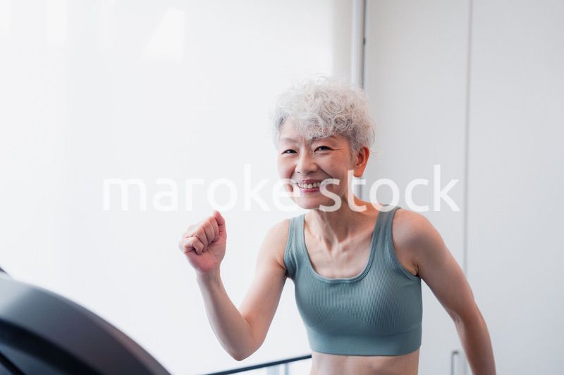 ジムでランニングマシンに乗るシニアの女性